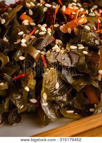 Seaweed Salad With Sesame Seeds Is On A White Plate
