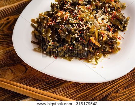 Seaweed Salad With Sesame Seeds Is On A White Plate