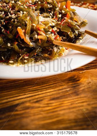 Seaweed Salad With Sesame Seeds Is On A White Plate