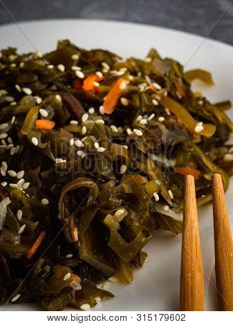 Seaweed Salad With Sesame Seeds Is On A White Plate
