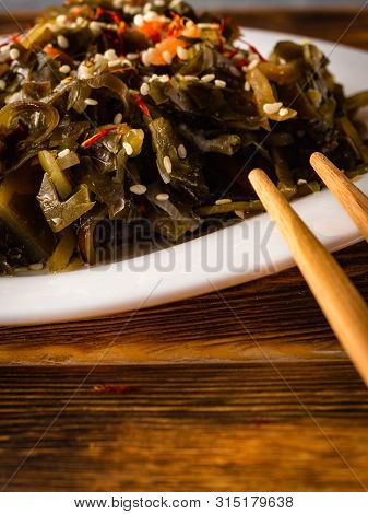 Seaweed Salad With Sesame Seeds Is On A White Plate
