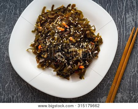 Seaweed Salad With Sesame Seeds Is On A White Plate