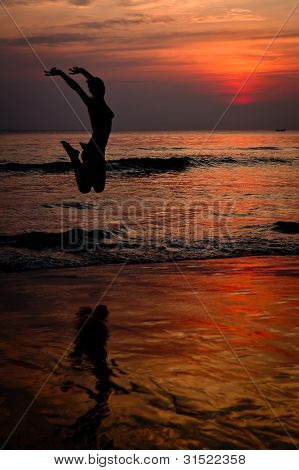 Carefree Woman Jumping On The Beach At Sunset