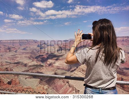 Girl Taking Photos In The Grand Canyon With Mobile Phone.