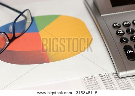 Grapical Diagram With Glasses And Calculator On A Desk