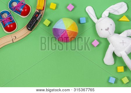 Baby Kids Toys Background With Toys Train, Colorful Wooden Blocks And Soft Plush Toys On Light Green