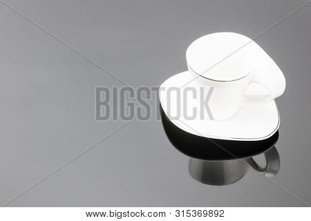 Porcelain Clay Cup For Coffee Or Tea With Sauser On The Grey Mirror Background. Copy Space.