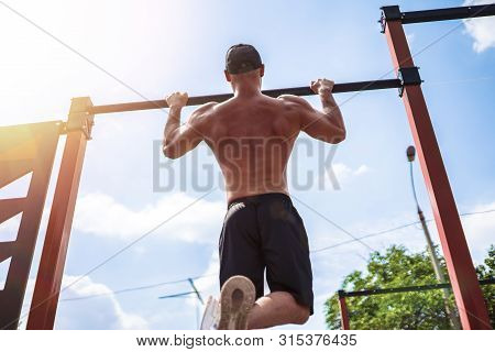 Brutal Athletic Man Making Pull-up Exercises On A Crossbar At Outdoor Streeet Gym.