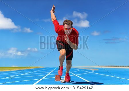 Runner athlete starting running at start of run track on blue running tracks at outdoor athletics and fiel stadium. Sprinter on race. Sport and fitness man sprinting.