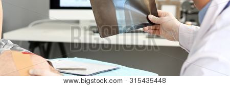 Smart Doctor Looking At X-ray Picture Of Patients Injured Leg. Concentrated Doc Man Touching Trouble