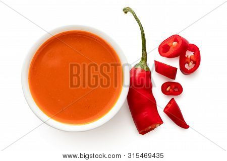 Peri Peri Chilli Sauce In A White Ceramic Bowl Next To A Cut Up Chilli Pepper Isolated On White From