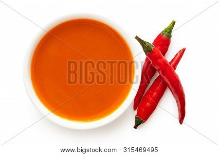 Peri Peri Chilli Sauce In A White Ceramic Bowl Next To Three Red Chillies Isolated On White From Abo