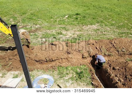 The Excavator Digs A Trench In A Private Area To Lay The Electrical Cable To The House.