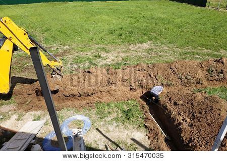 The Excavator Digs A Trench In A Private Area To Lay The Electrical Cable To The House.