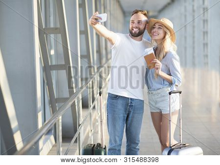 Our Vacation Starts. Excited Couple Making Selfie At Airport Terminal, Copy Space