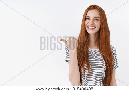 You Better See It. Charming Lively Happy Smiling Redhead Girl Blue Eyes Pointing Thumb Left Giving D