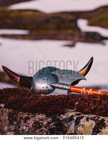 Equipment Of Viking Or Barbarian Warrior Outdoor On Nature. Viking Helmet With Axe On Brown Fur Of T