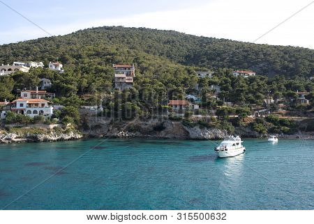 Greece, The Pine Clad Island Of Angistri. Pleasure Boats Near The Rocky Shore.  Holiday Villas On Th
