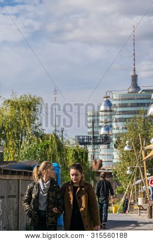 Berlin, Germany - September 26, 2018: Distracted Blonde And Brunette Girls Walking Arm-in-arm At The