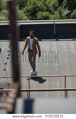 Selective Focus Of Stylish African American Businessman Riding Lonboard On Rooftop