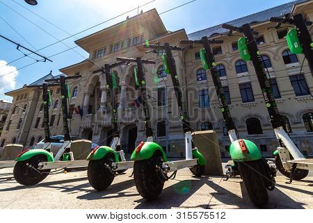 Bucharest, Romania - August 05, 2019: Several Lime-S Electric Scooters are parked on a sidewalk across the road from the Bucharest City Hall. This image is for editorial use only.