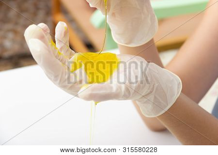 Young Beautiful Girl Shows How To Make Slime.. Hands In Medical Gloves And A Flask With A Yellow Liq
