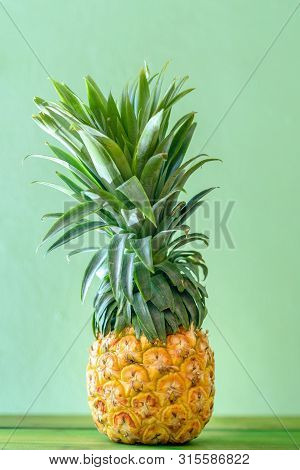Pineapple On Wooden Table Over Neo Mint Background. Tropical Summer Vacation And Beach Party.