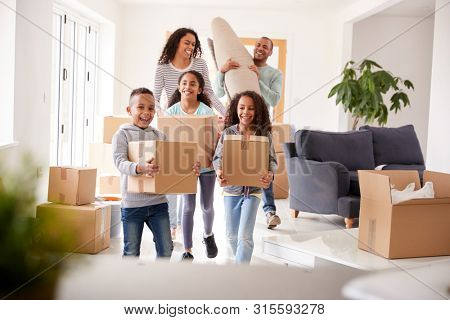 Smiling Family Carrying Boxes Into New Home On Moving Day