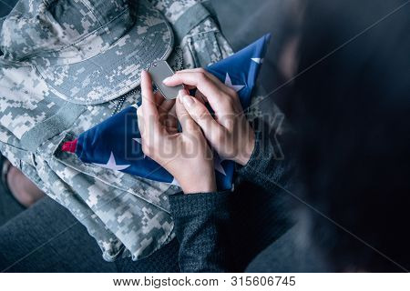 Cropped View Of Woman On Couch With Military Clothing, Tag Dog And Foded American Flag At Home