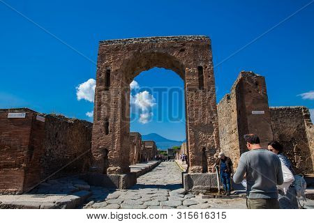 Pompeii, Italy - April, 2018: Tourists At The Arch Of Caligula In The Ancient City Of Pompeii