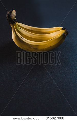 Three Bananas On Dark Background Shot At Shallow Depth Of Field