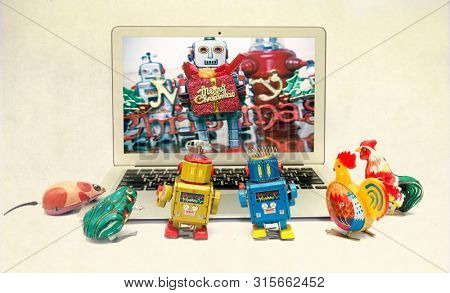 retro tin toys looking at a there friends celerbrating Christmas on a laptop computer 