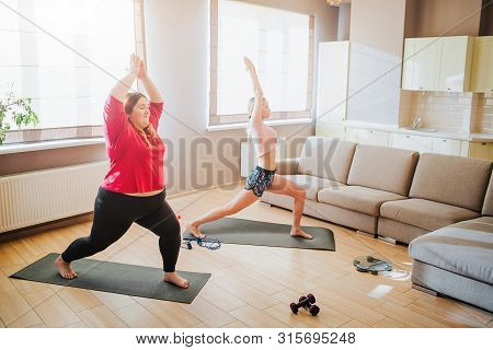 Youbng Plus Size Model And Well-built Woman Doing Exercise Together. Stretching Up And Standing In Y