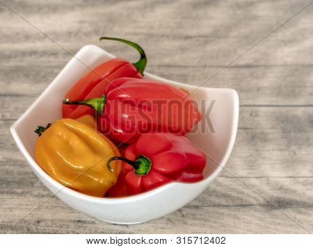 Habanero Pepper In A White Bowl On A Wooden Table.