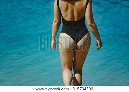 Woman In Black Swimsuit At Sand Beach View From Behind Summer Vacation