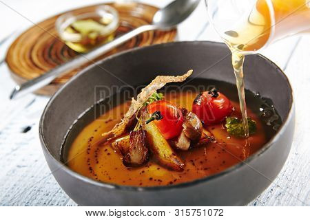 Restaurant Soup Food - Delicious Mushroom Soup with Garlic and Cherry Tomato. Gourmet Restaurant Soup Menu. Mushrooms Soup Garnished with Tea Broth and Garlic Mousse