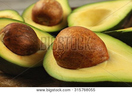 Avocado Fruits Cut In Half, Seed Visible, Close Up Photo, Showing Structure On Brown Pit.