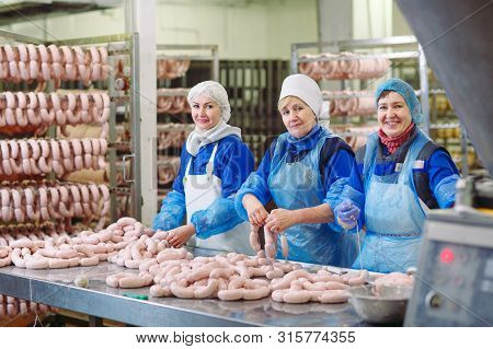 Butchers Processing Sausages At The Meat Factory.