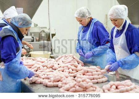 Butchers Processing Sausages At The Meat Factory
