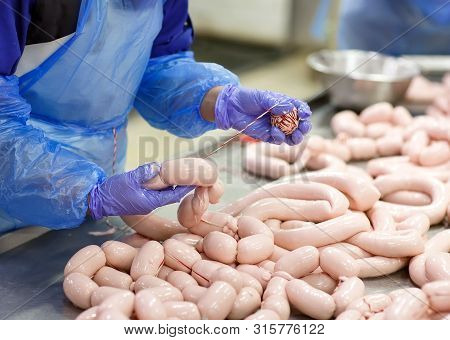 Butchers Processing Sausages At The Meat Factory