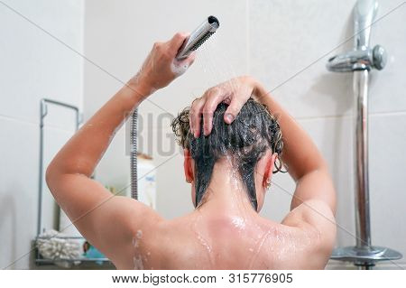 Woman Washing Her Hair With A Lot Of Foam Inside A Shower. Back View Of Young Woman Washing Her Hair