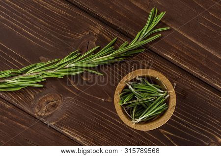 One Whole Lot Of Pieces Of Fresh Evergreen Sprig Of Rosemary In A Wooden Bowl Flatlay On Brown Wood