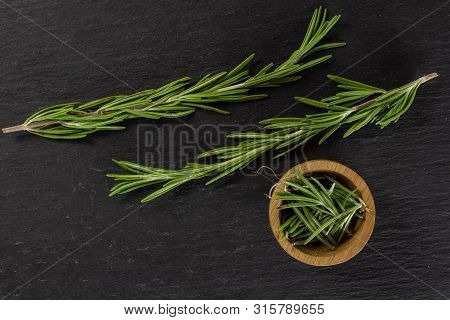 Group Of Two Whole Lot Of Pieces Of Fresh Evergreen Sprig Of Rosemary In A Wooden Bowl Flatlay On Gr