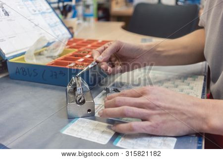 Woman locksmith repairing a lock using tool to measure a part