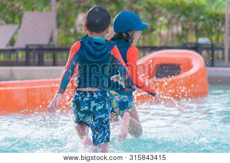 Two Asian Siblings In Playing Together In Water Aqua Park Pool.
