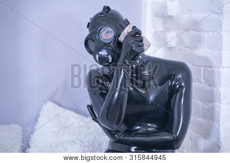 Morning Cup Of Tea Breakfast. Fetish Male In Rubber Black Suit At White Windowsill.