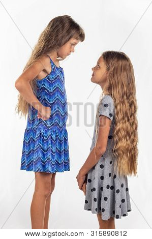 Two Girls Of Different Stature, One Of Them Stood On A Chair To Be Taller Than The Other
