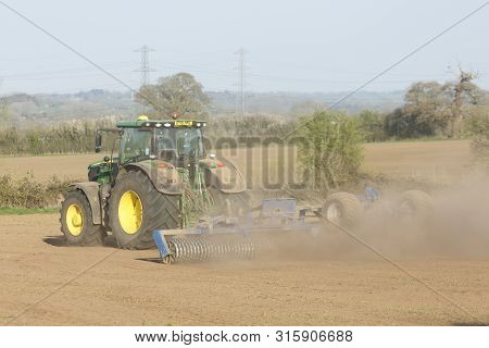 Buckingham, Uk - April 01, 2019. A John Deere Tractor Cultivates Land During A Drought Using A Cambr