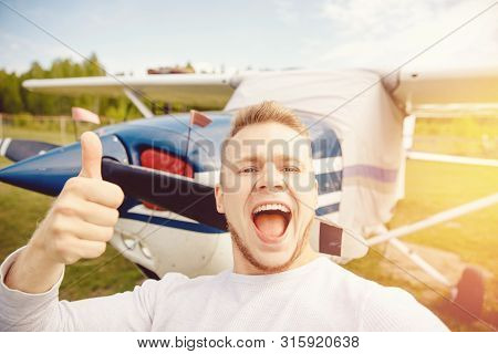 Happy Male Pilot Selfie Photo Aviator Smiling On Background Propeller Driven Aircraft. Travel Rental