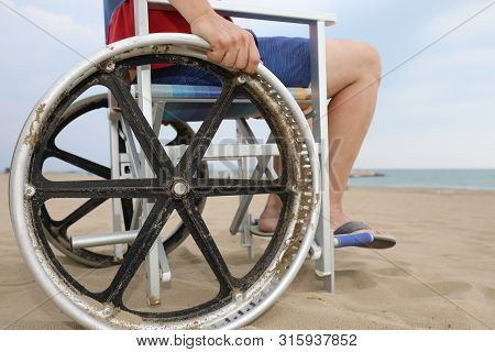 Detail Of A Special Wheelchair With Big Wheels To Move On The Sandy Beach Of The Resort With A Young